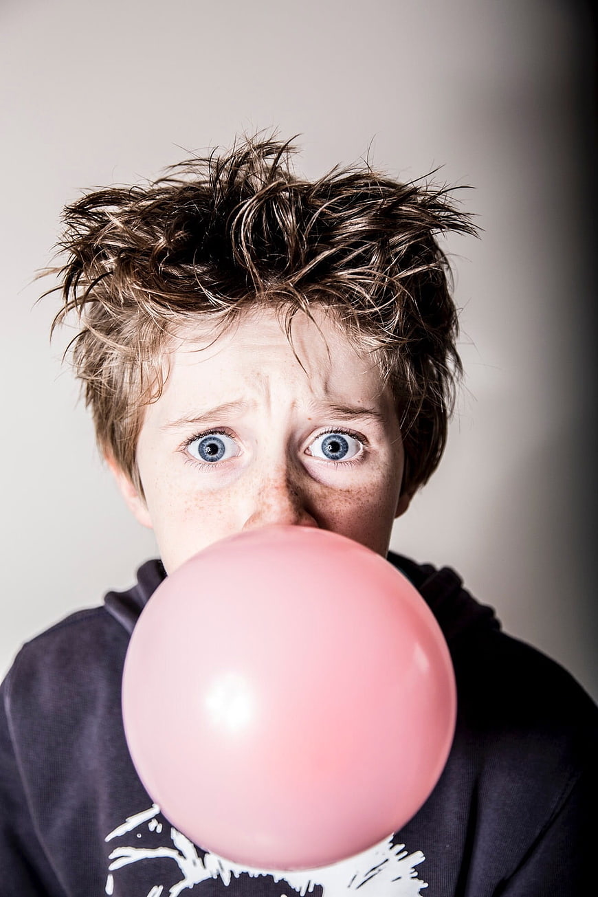 Boy blowing large pink bubble gum bubble