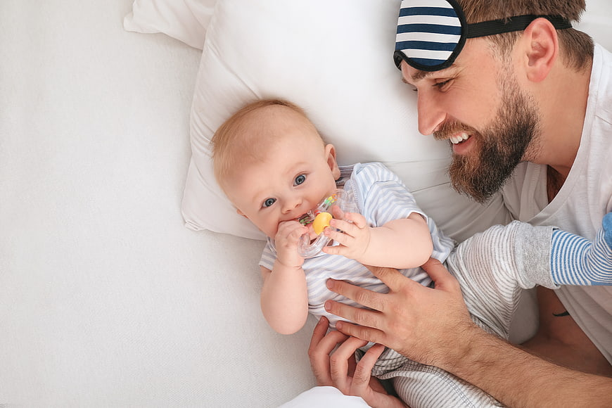 Happy Father and Baby Playing in Bed with Sleep Mask