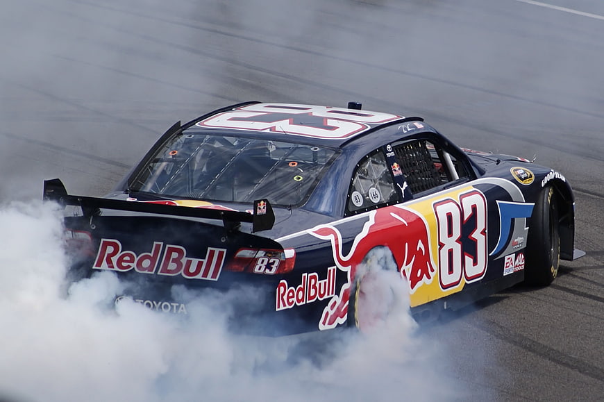 NASCAR Red Bull car performing burnout with smoke