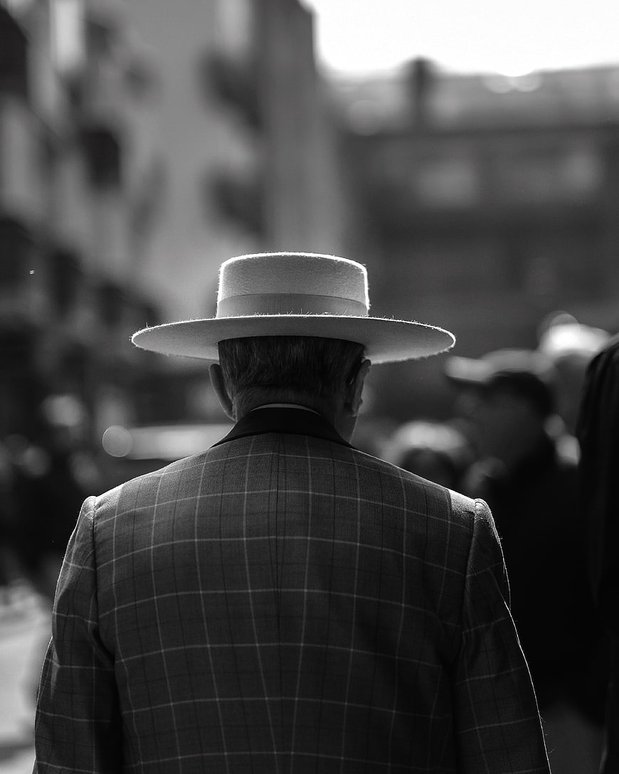 Man in Fedora and Plaid Suit Walking Away in Black and White