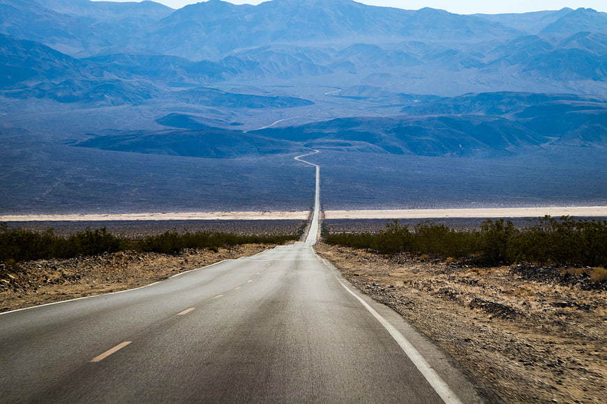 Straight Desert Highway Stretching to Distant Blue Mountains