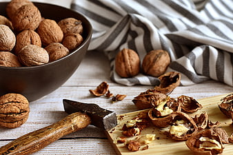 Walnuts in shell with rustic hammer and wooden board