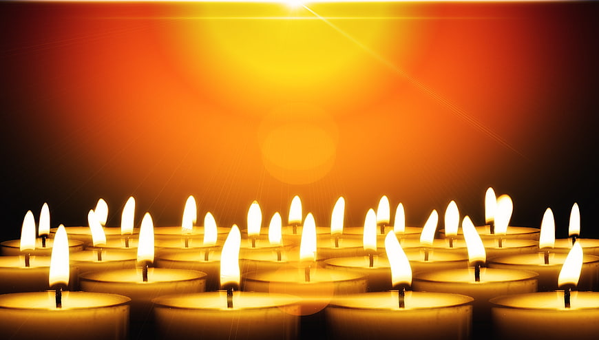Rows of glowing tea light candles with warm golden background