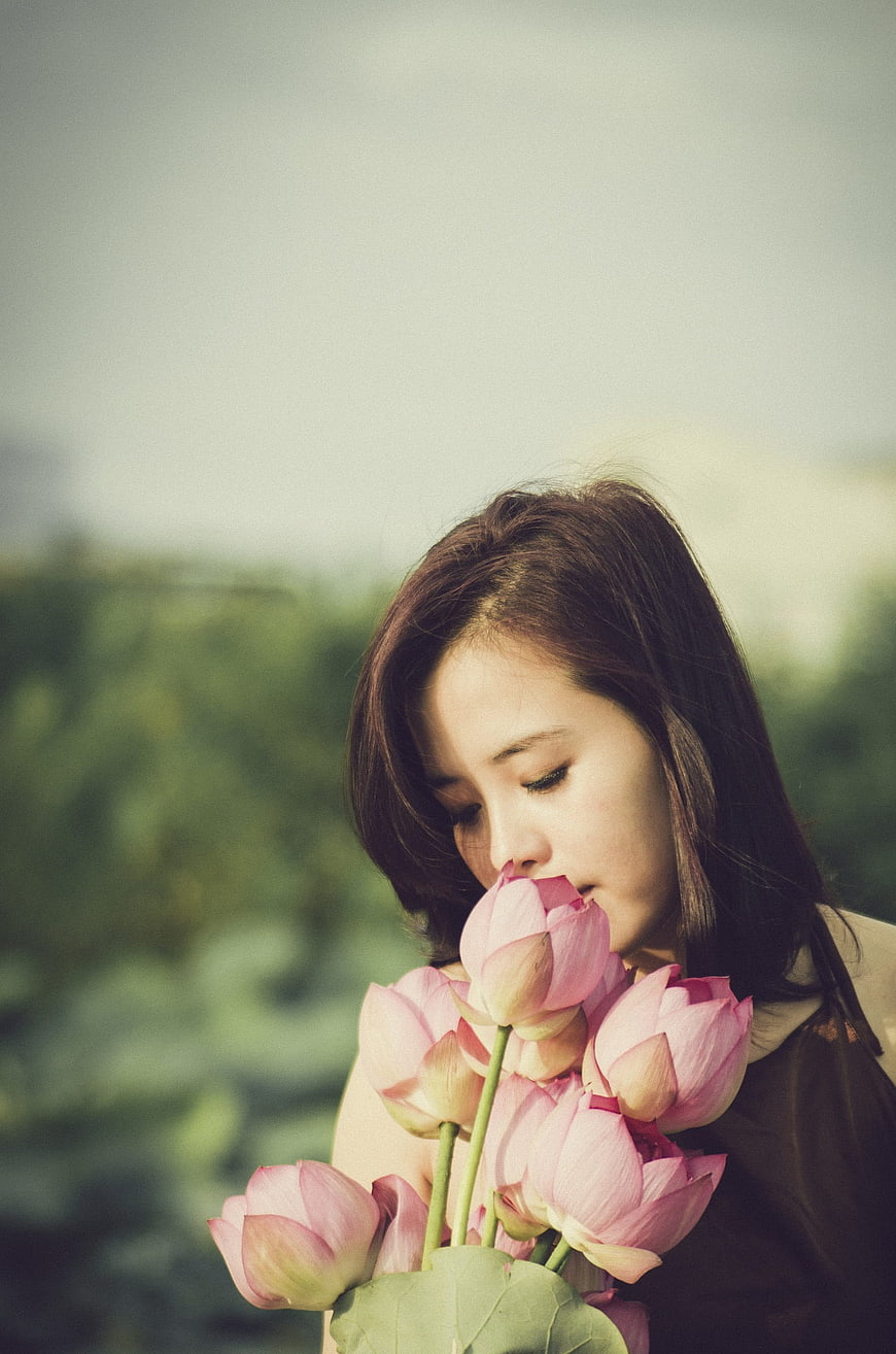 Young Woman Smelling Pink Lotus Flowers in Nature