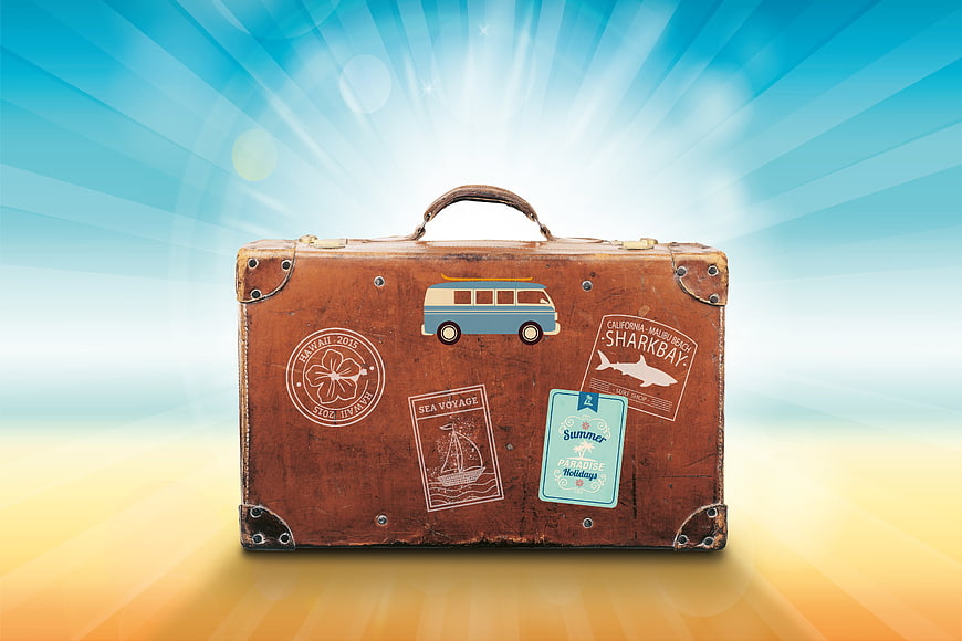 Vintage suitcase with travel stickers on sunny background
