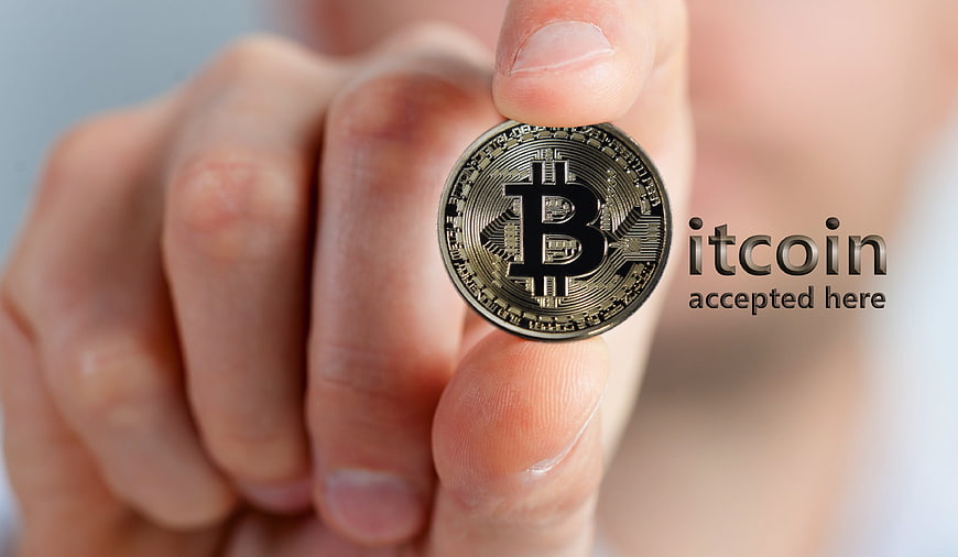 Hand holding physical Bitcoin coin with accepted here text