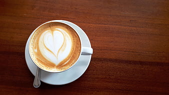 Cappuccino with heart latte art on a rustic wooden table