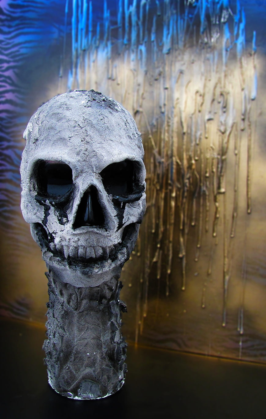 Handmade textured skull sculpture with dripping background