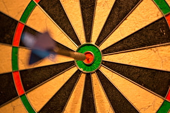Dart hitting bullseye on dartboard close up