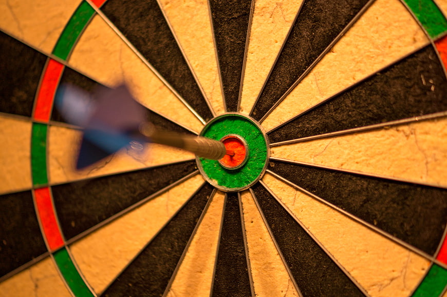 Dart hitting bullseye on dartboard close up