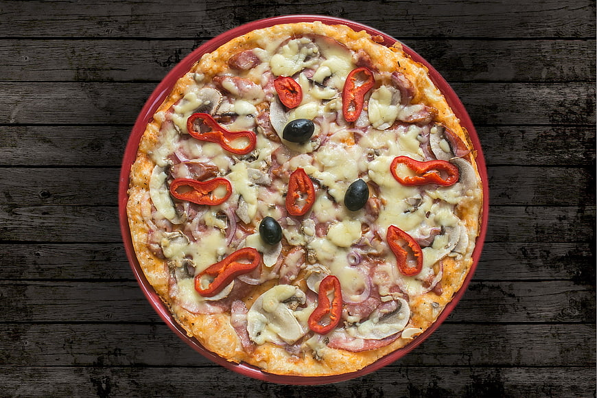 Top view of homemade pizza with ham, mushrooms, and peppers
