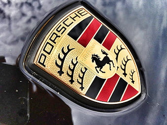 Close-up of a Porsche emblem on a dark car surface