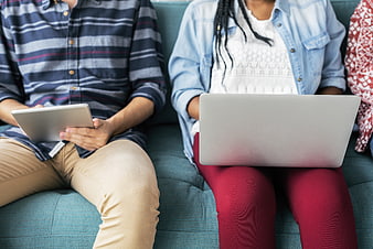 Young people using laptop and tablet on teal couch