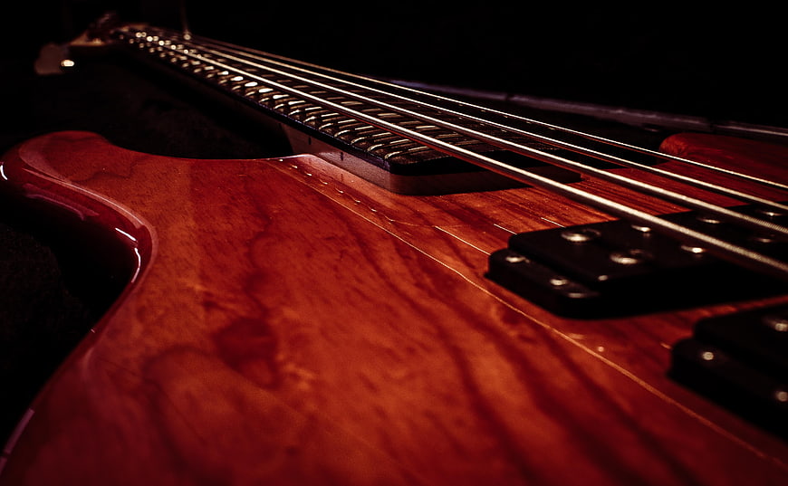 Close-up of red electric bass guitar body and strings
