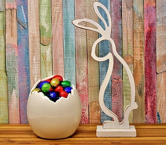 Easter bunny silhouette and chocolate eggs on colorful wood