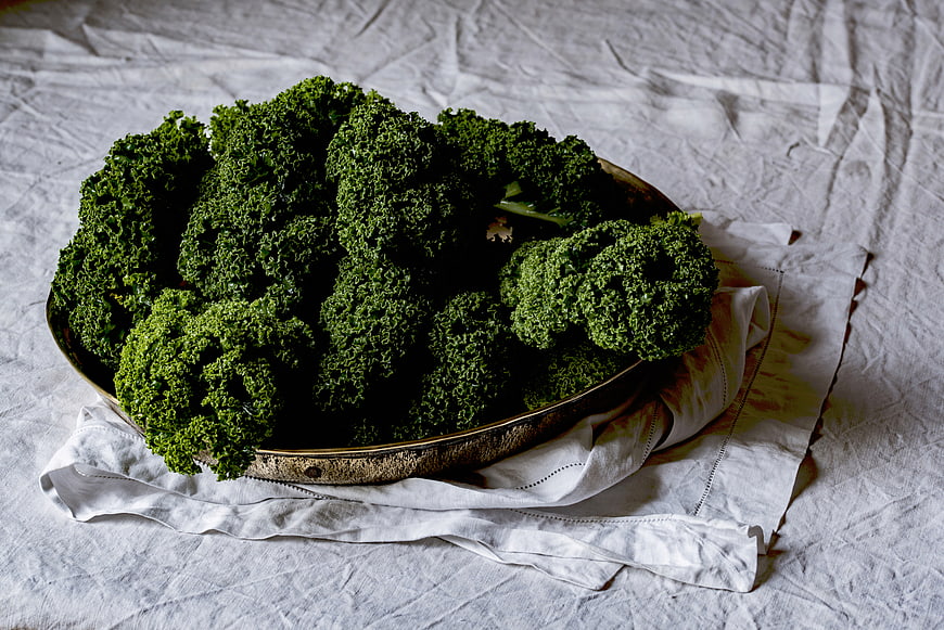 Fresh curly kale in a rustic metal bowl on linen