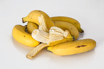 Ripe Yellow Bananas with Peeled Fruit on White Background