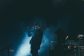 Silhouette of male singer performing on stage with blue spotlight