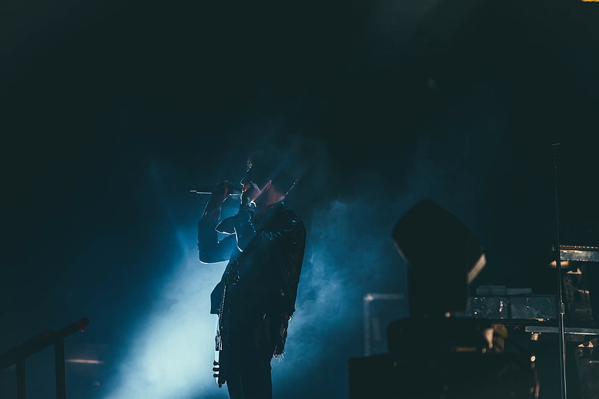 Silhouette of male singer performing on stage with blue spotlight