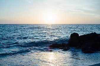 Sunset over ocean waves crashing on rocky shore