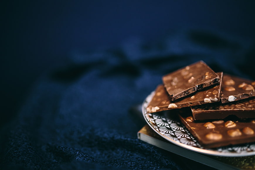Dark Chocolate Bars with Nuts on Blue Background