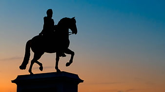 Silhouette of equestrian statue against sunset sky