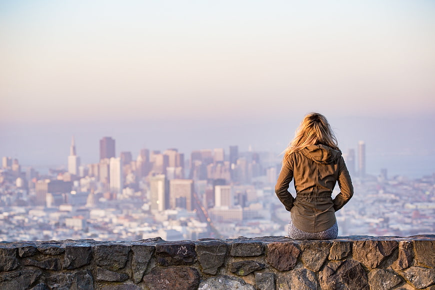 Woman Sitting on Wall Overlooking San Francisco Skyline