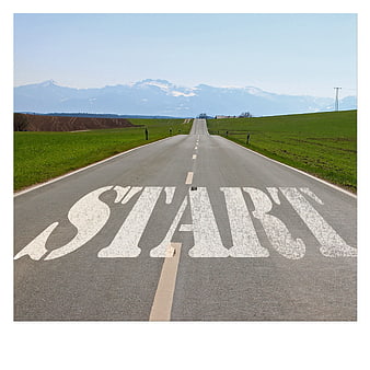 START painted on asphalt road leading to mountains