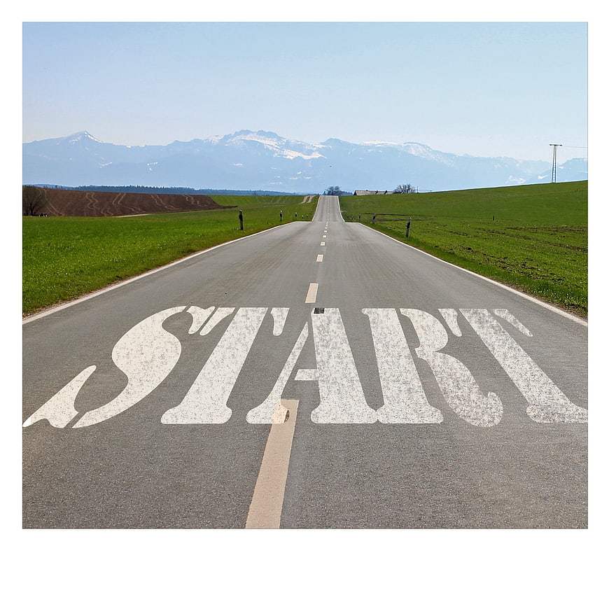 START painted on asphalt road leading to mountains