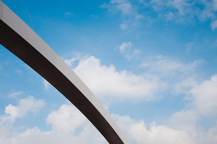 Modern concrete arch bridge against blue sky with clouds