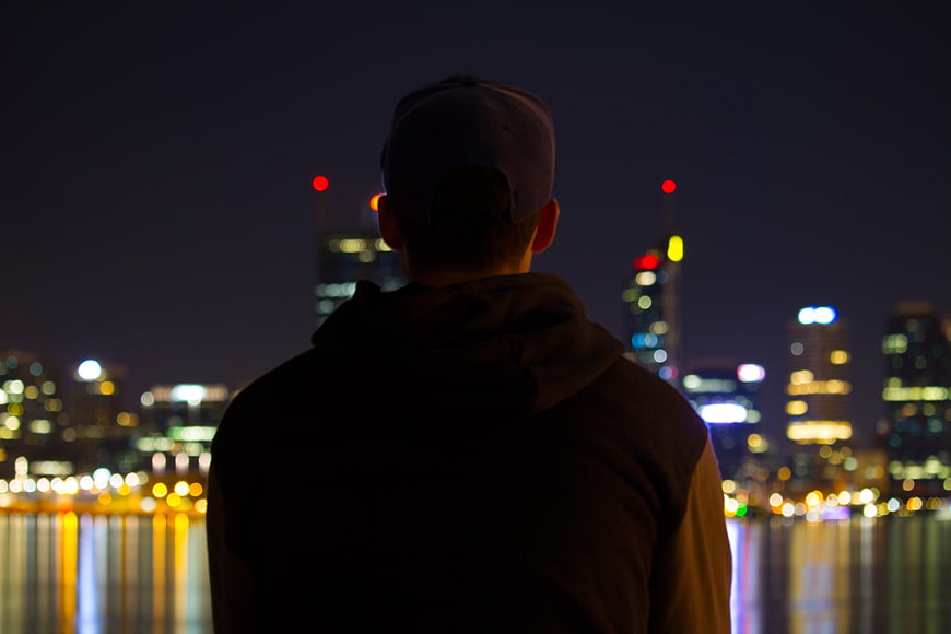 Silhouette of Man Looking at City Skyline at Night