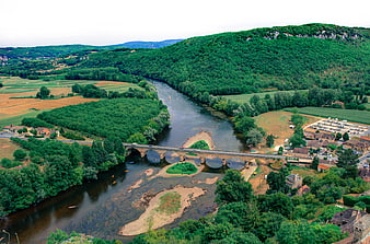 Aerial view of Dordogne river with stone bridge and lush green hills
