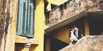 Wedding Couple Kissing on Weathered Yellow Building Stairs