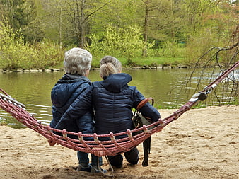 Two Senior Women Relaxing in Hammock by Pond