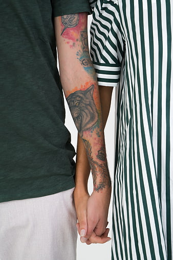 Couple holding hands with wolf tattoo on arm