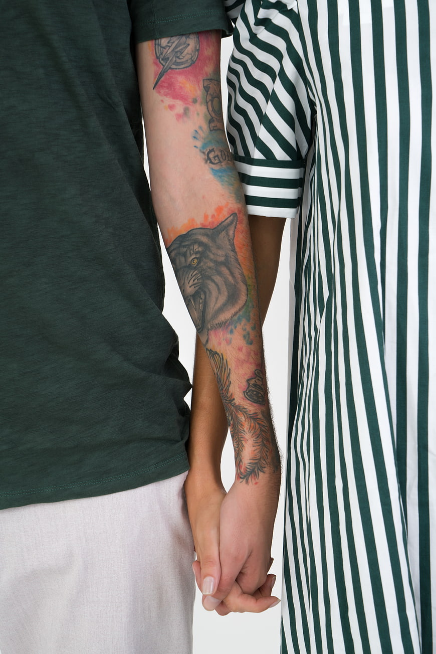 Couple holding hands with wolf tattoo on arm
