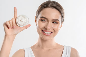 Happy woman holding jar of white face cream