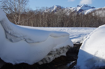 Snow-covered stream in Kamchatka winter landscape with mountains