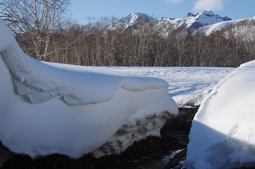 Snow-covered stream in Kamchatka winter landscape with mountains