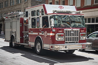 Red and white fire truck driving on city street