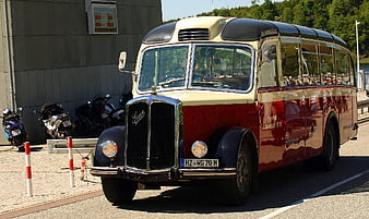 Vintage red and cream bus parked on sunny street