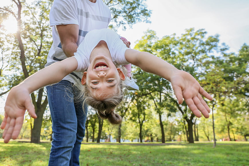 Happy Father Holding Upside Down Daughter in Park