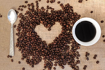 Coffee beans arranged in heart shape with cup of black coffee