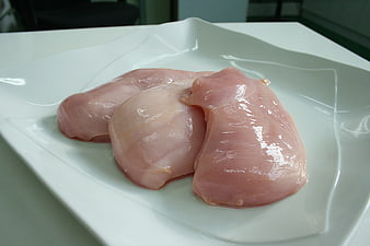 Raw chicken breasts on a white plate