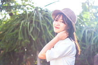 Young woman in straw hat smiling in garden sunlight