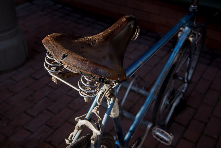 Close-up of vintage blue bicycle with worn leather saddle