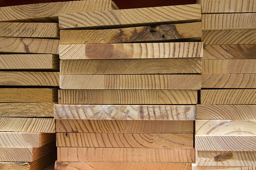 Stack of raw lumber planks with natural wood grain texture