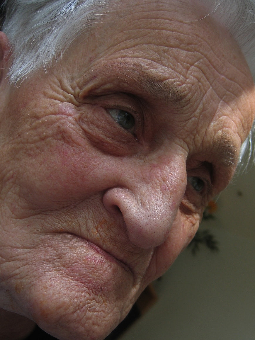 Close-up portrait of elderly woman with wrinkled face and age spots