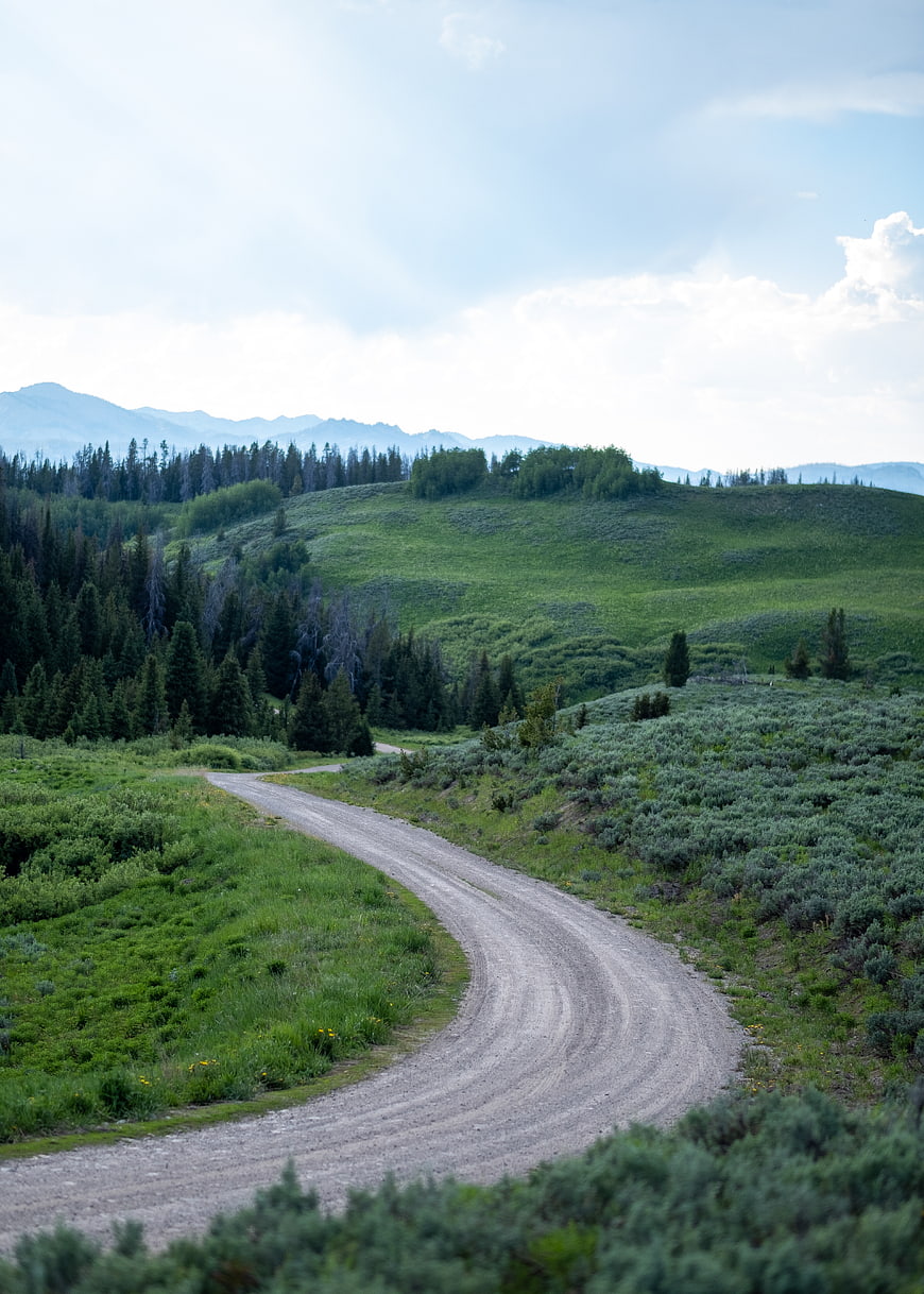 Winding gravel road through green mountain landscape