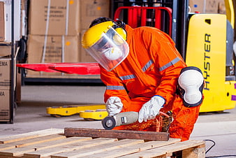 Warehouse worker grinding metal with angle grinder